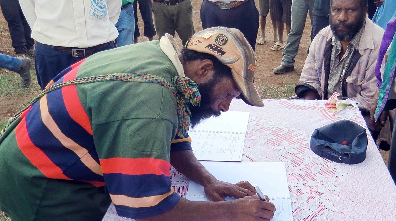 A clan member signing the peace agreement document.