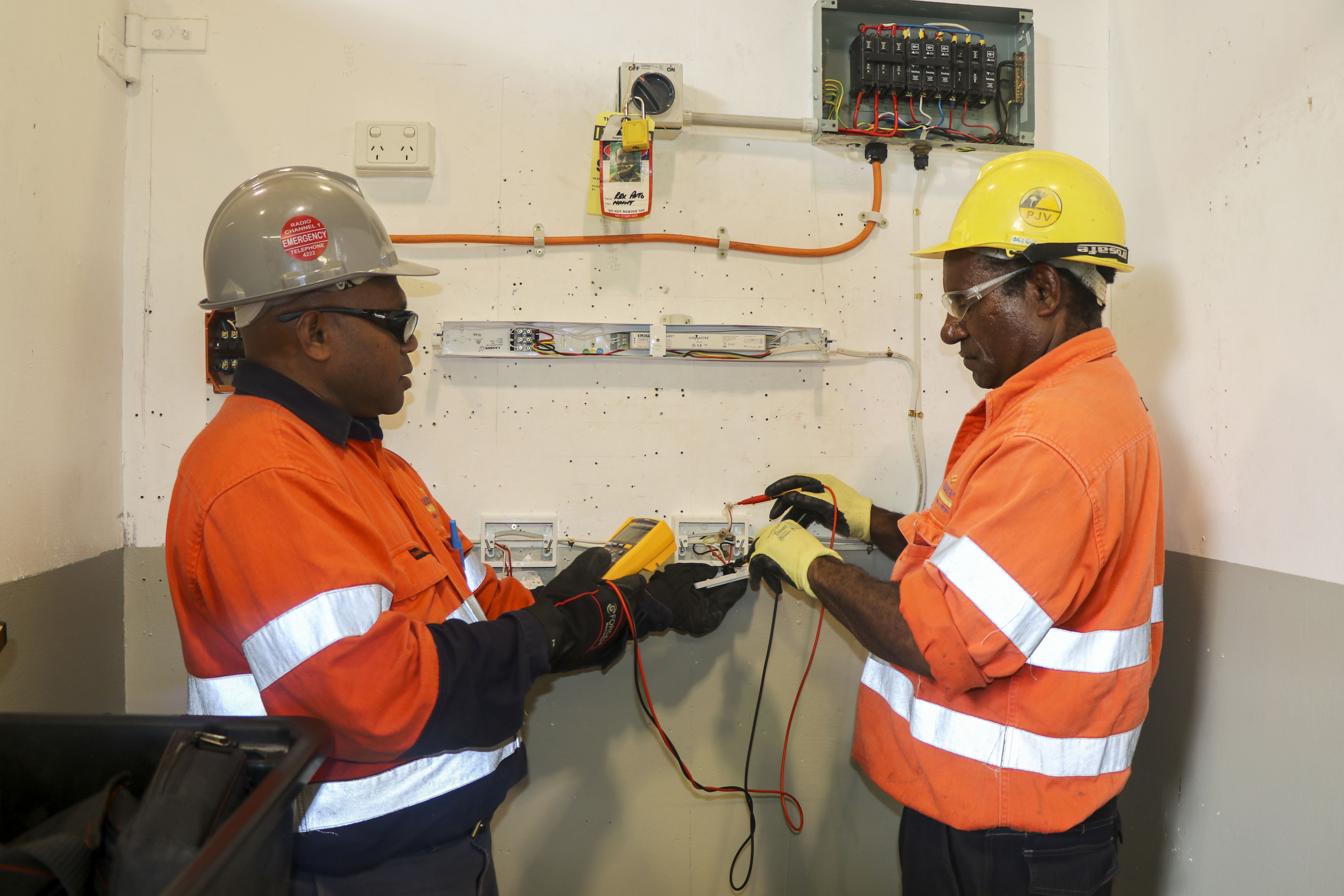 A PJV electrical trade test candidate (right) prepares equipment for electrical installation under the watchful eyes of trainer Tommy Aselai
