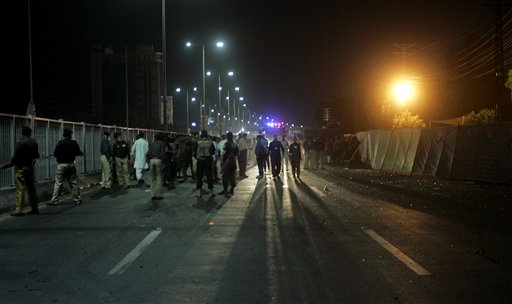 Pakistani police officers gather at the site of suicide bombing on a road leading to Gaddafi Stadium late night on Friday
