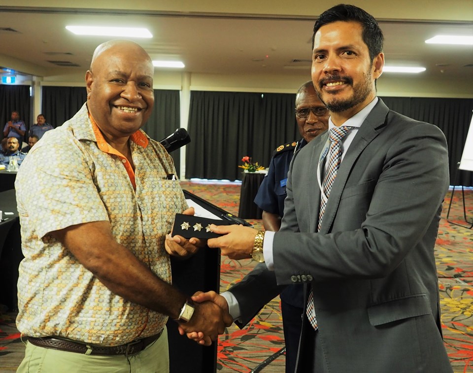 Detective Senior Sergeant Apollos Terry being conferred with the rank of inspector by Police Minister Bryan Kramer, with Police Commissioner Gari Baki in the background